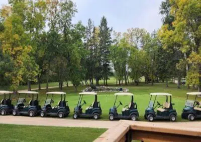 Electric golf carts parked neatly at Harbour Golf at Innisfil, situated near CozyCotts, ready to transport players around the meticulously manicured fairways and scenic greens of the course.