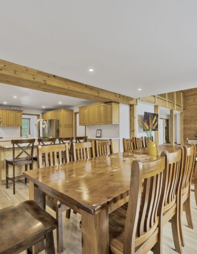 Open kitchen and dining area with wooden furniture, stone fireplace, and recessed lighting.