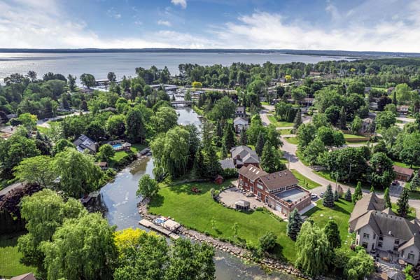 Living room with wooden walls, large windows, dark leather sectional sofa, and glass coffee table.