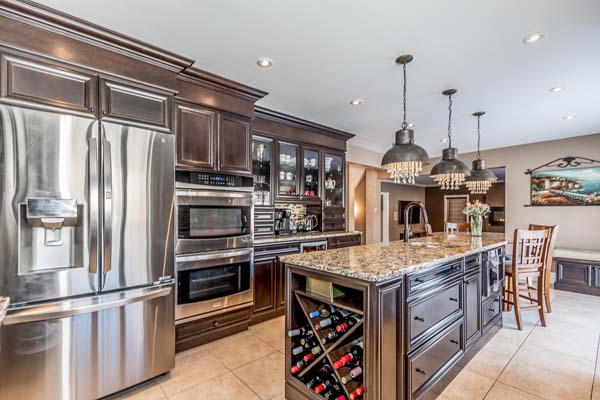 Two people in yellow life jackets paddling a green kayak on a lake surrounded by trees.